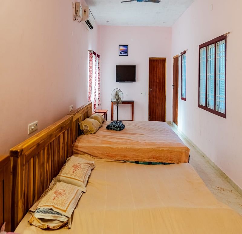 Pink-walled group room with beds side by side and a TV