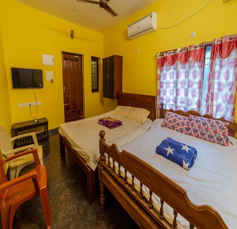 Spacious yellow group room with beds, TV and floral curtains