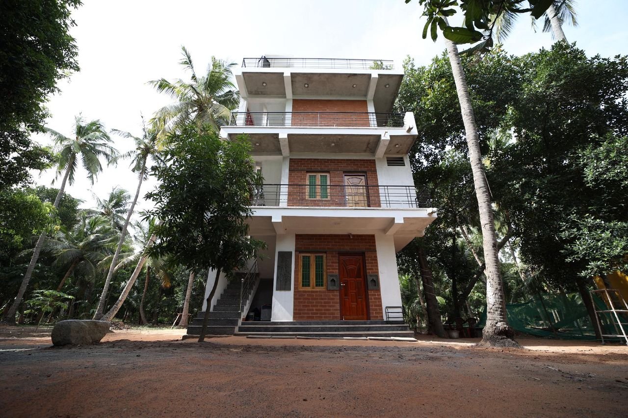 The farmhouse front with palms, balconies and brick detailing in warm light
