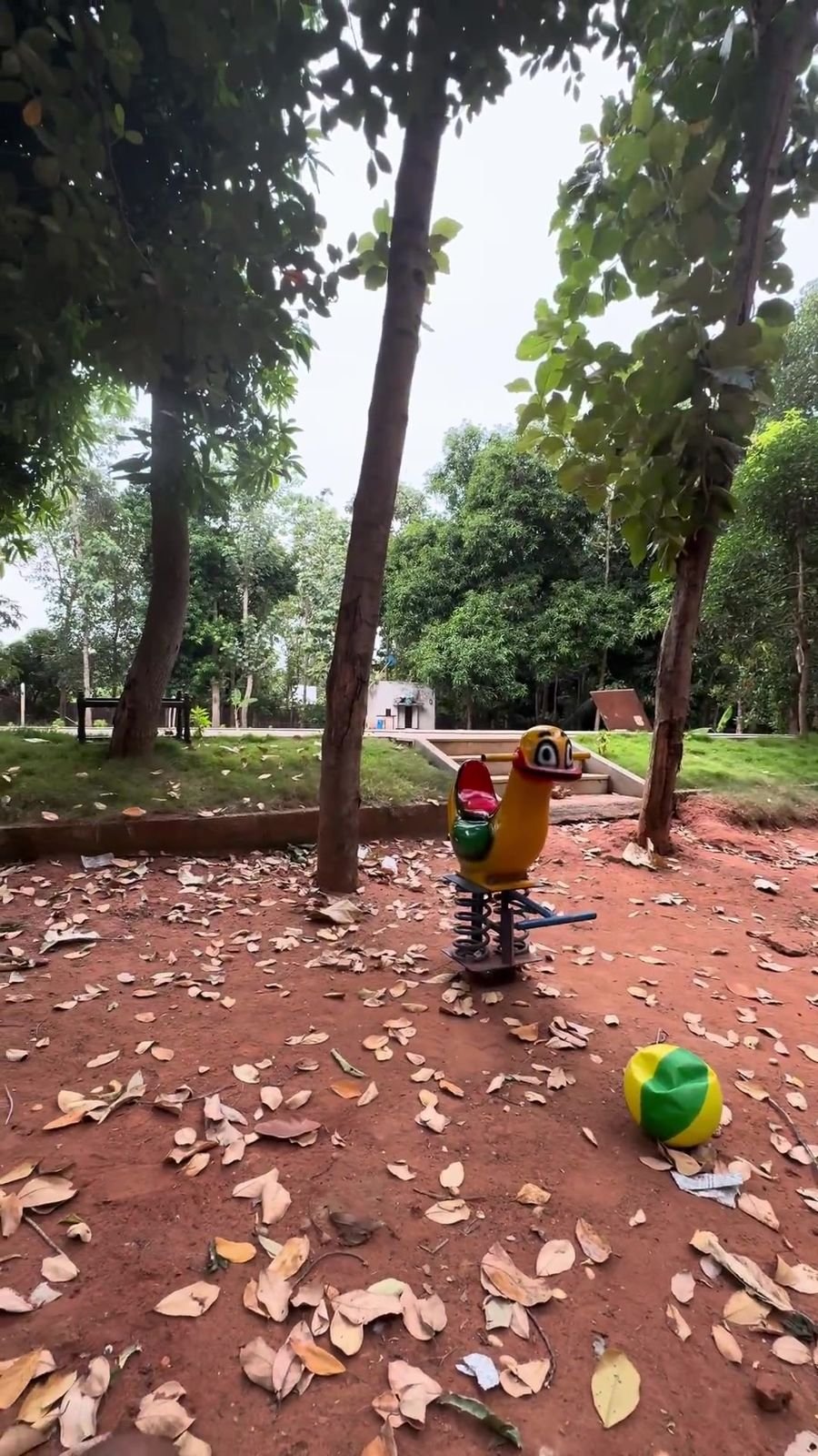 Bird-shaped spring rider on red earth under the trees